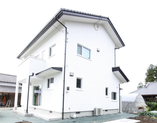 白い外壁とダークグレーの瓦屋根が調和するシンプルモダンな外観